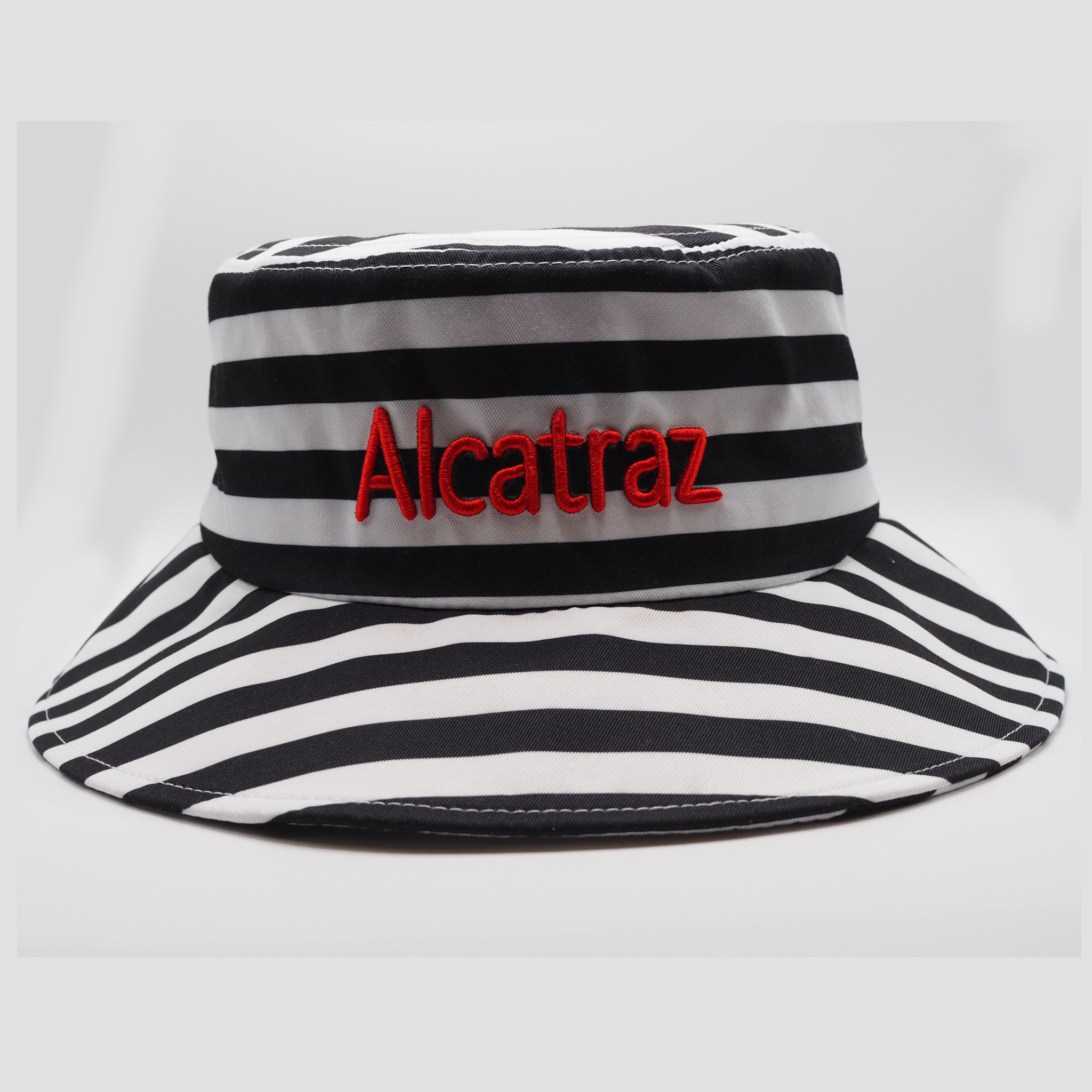 Black and white stripe bucket style hat with "Alacatraz" embroidered in red on the front of the hat.